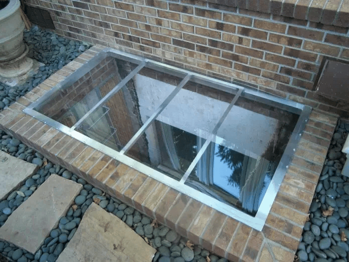 Brick-faced window well fitted with a cover