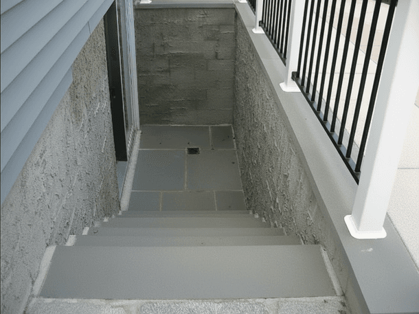 Basement stairwell with a drain and railing